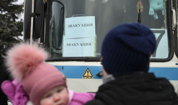 Мужчина с ребенком стоит возле автобуса во время эвакуации из Горловки